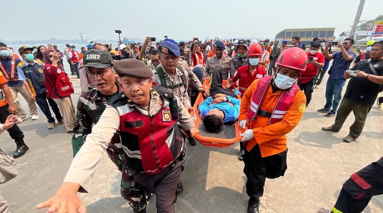 In this photo taken with a smartphone, rescuers carry a survivor from a passenger ferry overturned in bad weather in the Java Sea on a stretcher upon arrival at a port in Banjarmasin, South Kalimantan, Indonesia, Tuesday, Sept. 15, 2026. (AP Photo/Iman Satria)