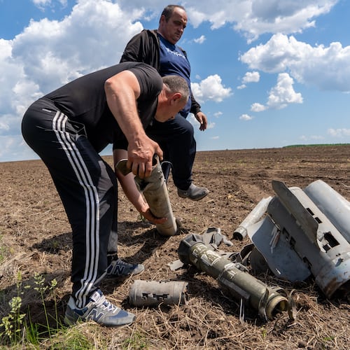Farmers collect fragments of a Russian missile that hit an agricultural field near the front line in the Kharkiv region, Ukraine, Friday, May 22, 2026. (AP Photo/Andrii Marienko)