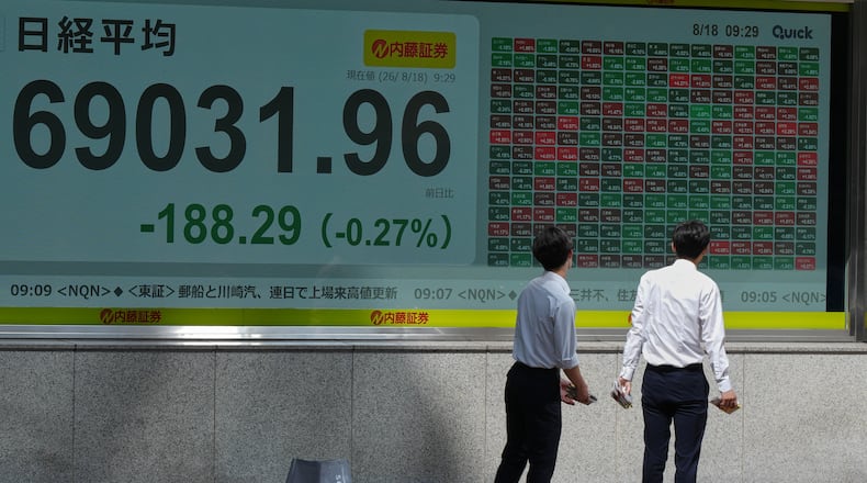 People look at an electronic stock chart board showing Japan's Nikkei index at a securities firm Tuesday, Aug. 18, 2026, in Tokyo. (AP Photo/Eugene Hoshiko)