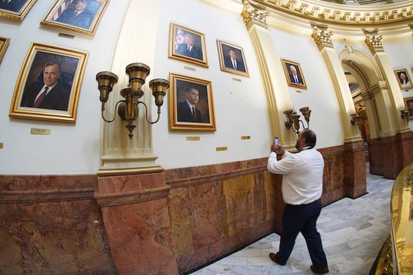 A man takes a photograph of the plaque that marked the placement of a portrait of President Donald Trump after the picture, which was part of a display of all of the country's chief executives, was removed from the wall of the rotunda in the State Capitol following complaints about the likeness from Trump Tuesday, March 25, 2025, in Denver. (AP Photo/David Zalubowski)