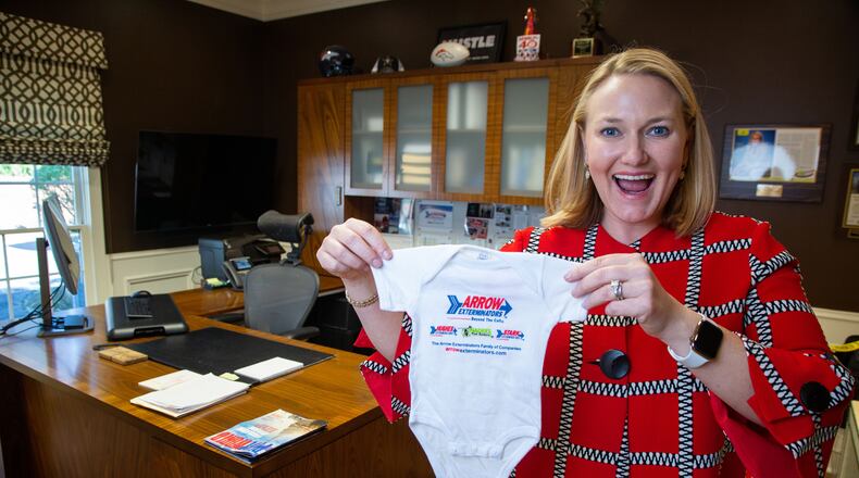 Arrow Exterminators CEO and President, Emily Thomas Kendrick, holds up a baby onesie with the company logo on it at their National Headquarters in Atlanta. She started a tradition of giving one to every employee who had a new born baby.