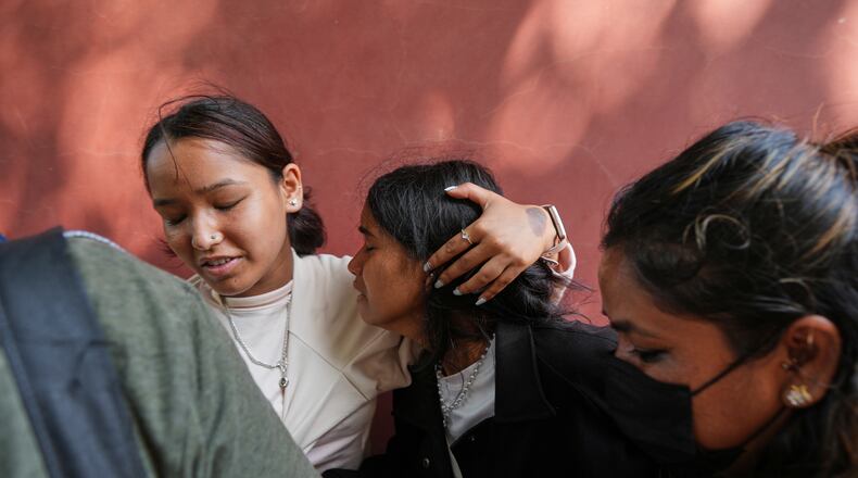 A relative consoles Jenisha, center, as she cries while waiting for the news of her father missing after flash flooding in Nepal's Nuwakot district, Friday, Aug. 28, 2026. (AP Photo/Rajesh Kumar Singh)