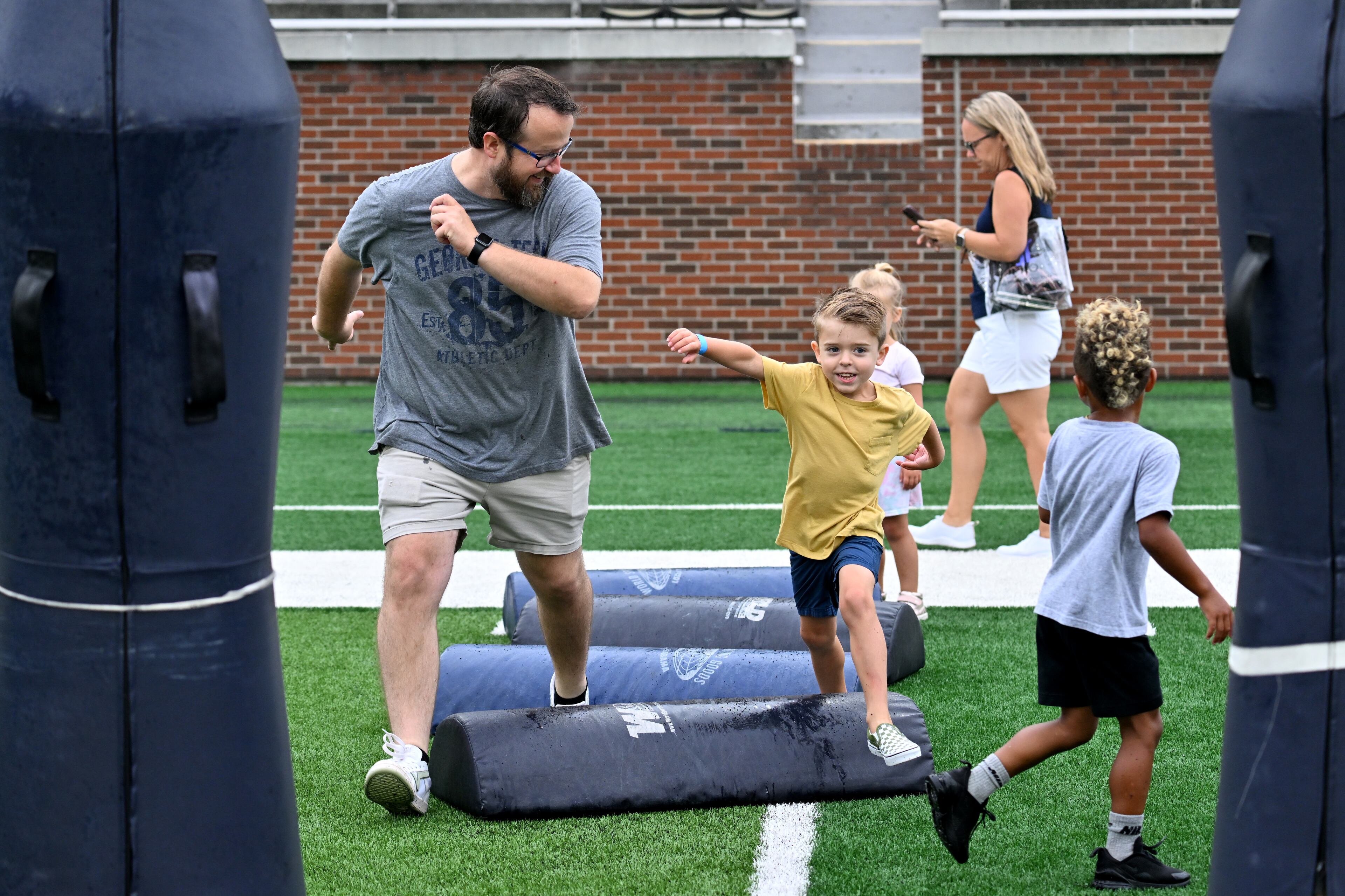 Kris Bordeaux (left) and J.T. Johnson, 5, enjoy a variety of entertaining activities during the annual “First Saturday on The Flats” at Bobby Dodd Stadium, Saturday, August 2, 2025, in Atlanta. The Flats provides Tech fans with the opportunity to engage with their favorite Yellow Jackets ahead of the upcoming 2025 season. The event offers a variety of entertaining activities for the whole family, including a DJ, autograph opportunities, tailgate games and interactive experiences right on the field at Bobby Dodd Stadium. (Hyosub Shin / AJC)