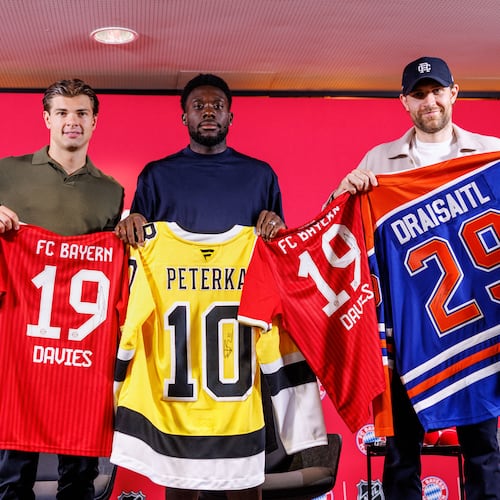 Boston Bruins’ John-Jason Peterka, from left, FC Bayern Munich’s Alphonso Davies, and Edmonton Oilers Leon Draisaitl, pose with jerseys during a joint press conference by FC Bayern Munich and the National Hockey League, Thursday, Aug. 20, 2026, in Munich. (Matthias Balk/dpa via AP)