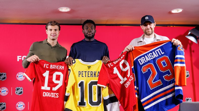 Boston Bruins’ John-Jason Peterka, from left, FC Bayern Munich’s Alphonso Davies, and Edmonton Oilers Leon Draisaitl, pose with jerseys during a joint press conference by FC Bayern Munich and the National Hockey League, Thursday, Aug. 20, 2026, in Munich. (Matthias Balk/dpa via AP)