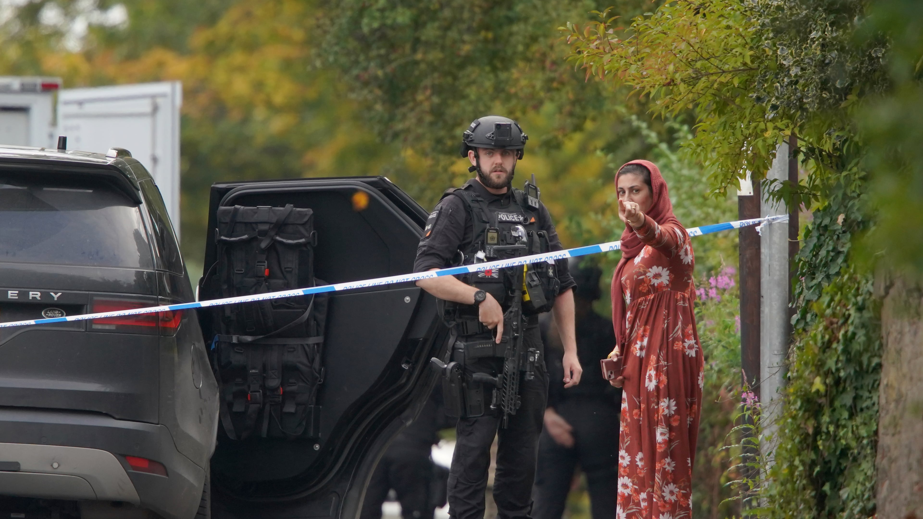 An armed police officer speaks to member of the public near the scene of a stabbing incident at Heaton Park Hebrew Congregation synagogue, in Crumpsall, Manchester, England, Thursday, Oct. 2, 2025. (AP Photo/Ian Hodgson)