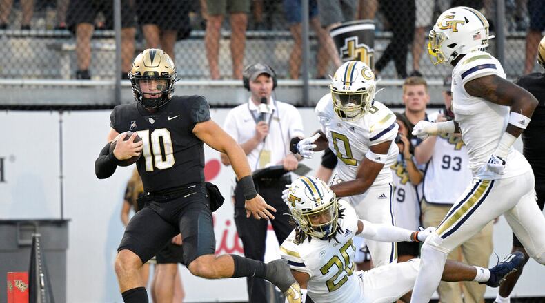 Central Florida quarterback John Rhys Plumlee (10) rushes for a 28-yard touchdown past Georgia Tech defensive backs LaMiles Brooks (20), Myles Sims (0) and Zamari Walton, right, during the second half of an NCAA college football game, Saturday, Sept. 24, 2022, in Orlando, Fla. (AP Photo/Phelan M. Ebenhack)
