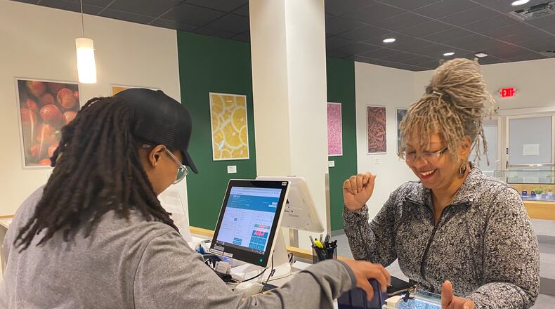 Sylvia Hayes, right, buys medical cannabis oil from Trulieve employee Shandra Patrick. Hayes, who got certified early for a low-THC card, wanted to have it ready once the medical dispensaries opened up in April. She uses the medical cannabis oil to help ease her chronic pain. (Helena Oliviero/helena.oliviero@ajc.com)