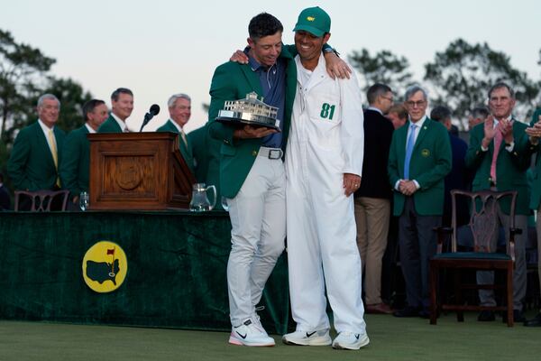Winner Rory McIlroy, of Northern Ireland, holds the trophy with caddie Harry Diamond at the Masters golf tournament, Sunday, April 13, 2025, in Augusta, Ga. (AP Photo/Ashley Landis)