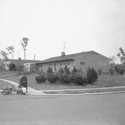 FILE - Two police patrol on the sidewalk, far left, in front of the newly-purchased home of William Myers, a black man who bought the house in this all-white community in Levittown, Penn, Aug. 16, 1957. (AP Photo/Bill Ingraham, File)