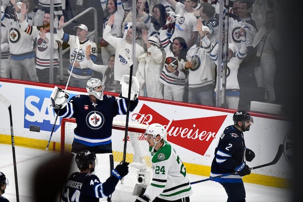 Winnipeg Jets goaltender Connor Hellebuyck (37) celebrates after an empty-net goal by Nikolaj Ehlers on the Dallas Stars during the third period of an NHL hockey playoff game in Winnipeg, Manitoba, Friday, May 9, 2025. (Fred Greenslade/The Canadian Press via AP)