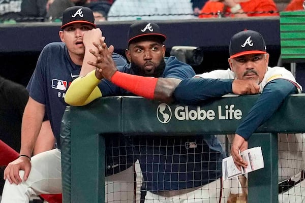 From left: Austin Riley, Marcell Ozuna and coach Eddie Perez watch Monday's game from the dugout.