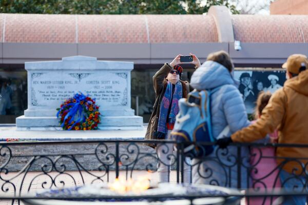 Seanna Johnson (center) of Midtown takes a photo of visitors by the eternal flame at the King Center at the Martin Luther King Jr. National Historic Site on Sunday, Jan. 18, 2026.  (Miguel Martinez/AJC)