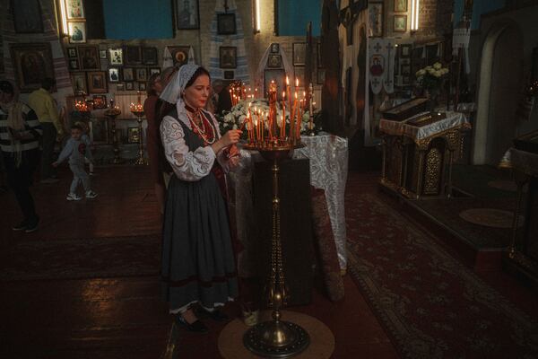 A woman lights a candle during the celebration of Orthodox Easter at St. John Theologian Church of the Orthodox Church of Ukraine in Kharkiv, Ukraine, on Sunday, April 20, 2025. (AP Photo/George Ivanchenko)