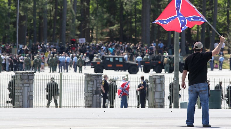 Joseph Andrews, one of a small group with the Rock Stone Mountain rally, waves a confederate battle flag towards a mass of counter-protesters more than 100 yards away at Stone Mountain Park on Saturday afternoon April 23, 2016 where a white power protest and two counter protests were scheduled.