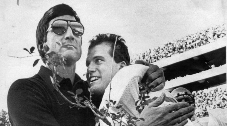 Georgia Tech quarterback John Dewberry gets a hug from Tech coach Bill Curry and a piece of the hedge that surrounds the playing field at Sanford Stadium in Athens, GA, following Tech's victory over Georgia.
