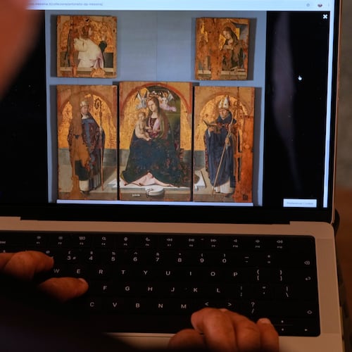 A journalist browses the Messina museum website showing a picture of the Early Renaissance painter Antonello da Messina's artwork where three of the five panels belonging to the Polyptych of San Gregorio and the double-sided panel with the Madonna and the Christ in Pietà, stolen from the Sicilian museum on Aug. 15, in Rome, Sunday, Aug. 16, 2026. (AP Photo/Gregorio Borgia)