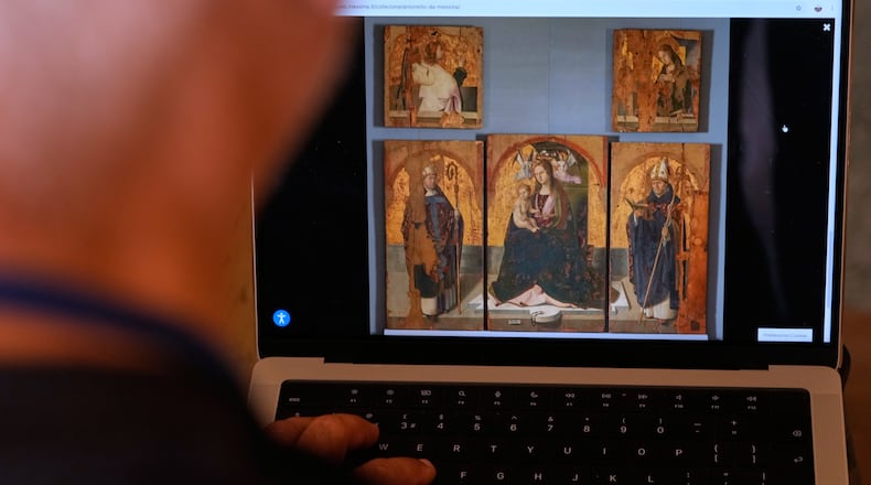 A journalist browses the Messina museum website showing a picture of the Early Renaissance painter Antonello da Messina's artwork where three of the five panels belonging to the Polyptych of San Gregorio and the double-sided panel with the Madonna and the Christ in Pietà, stolen from the Sicilian museum on Aug. 15, in Rome, Sunday, Aug. 16, 2026. (AP Photo/Gregorio Borgia)