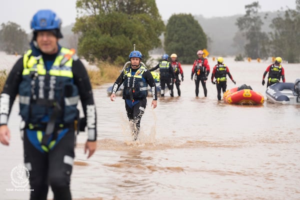 In this photo provided by the New South Wales Police, emergency workers wade through floodwaters as they prepare inflatable boats to effect rescues near Taree, Australia, Thursday, May 22, 2025. (NSW Police via AP)