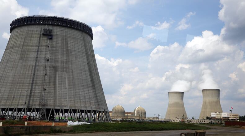 In this 2014 photo, a new cooling tower for a nuclear power plant reactor that's under construction stands near the two operating reactors at Plant Vogtle power plant in Waynesboro, Ga. AP/John Bazemore