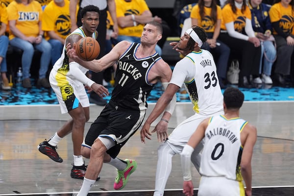 Milwaukee Bucks' Brook Lopez (11) heads to the basket past Indiana Pacers' Myles Turner (33) during the first half of a first-round NBA basketball playoff game, Saturday, April 19, 2025, in Indianapolis. (AP Photo/Michael Conroy)