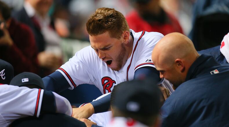 Freddie Freeman, Brian McCann and the rest of the Braves bury catcher Evan Gattis under a pile in the dugout after his solo home run in the fourth inning Wednesday against the Phillies.