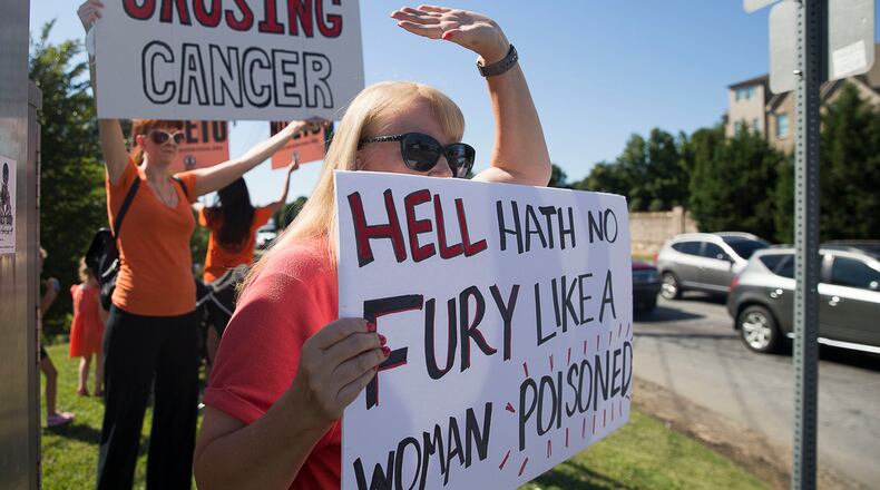 Jenni Shover holds a sign during a protest against the Sterigenics plant held Aug. 29 at the nearby intersection of Atlanta and Plant Atkinson roads. “I didn’t sign up to be anybody’s lab rat,” she told the AJC recently, “but that’s what I am.” ALYSSA POINTER / ALYSSA.POINTER@AJC.COM