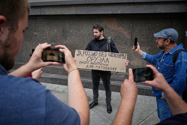 An activist holds a poster reading "For Russia without censorship. Orwell wrote a dystopia, not an instruction manual" during a picket against internet limitations in front of The State Duma, the lower house of the Russian Parliament, prior to consider the third and final reading of a bill, criminalising the search of "extremist materials" in Moscow, Russia, Tuesday, July 22, 2025. (AP Photo)
