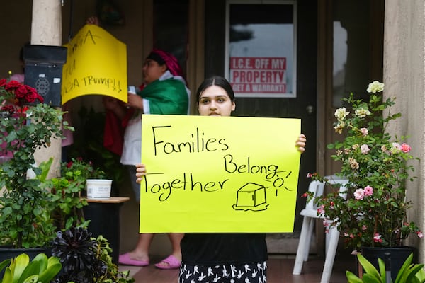 FILE - A resident holds a sign while protesting ICE presence and detentions on June 21, 2025, in Pasadena, Calif. (AP Photo/Damian Dovarganes, file)
