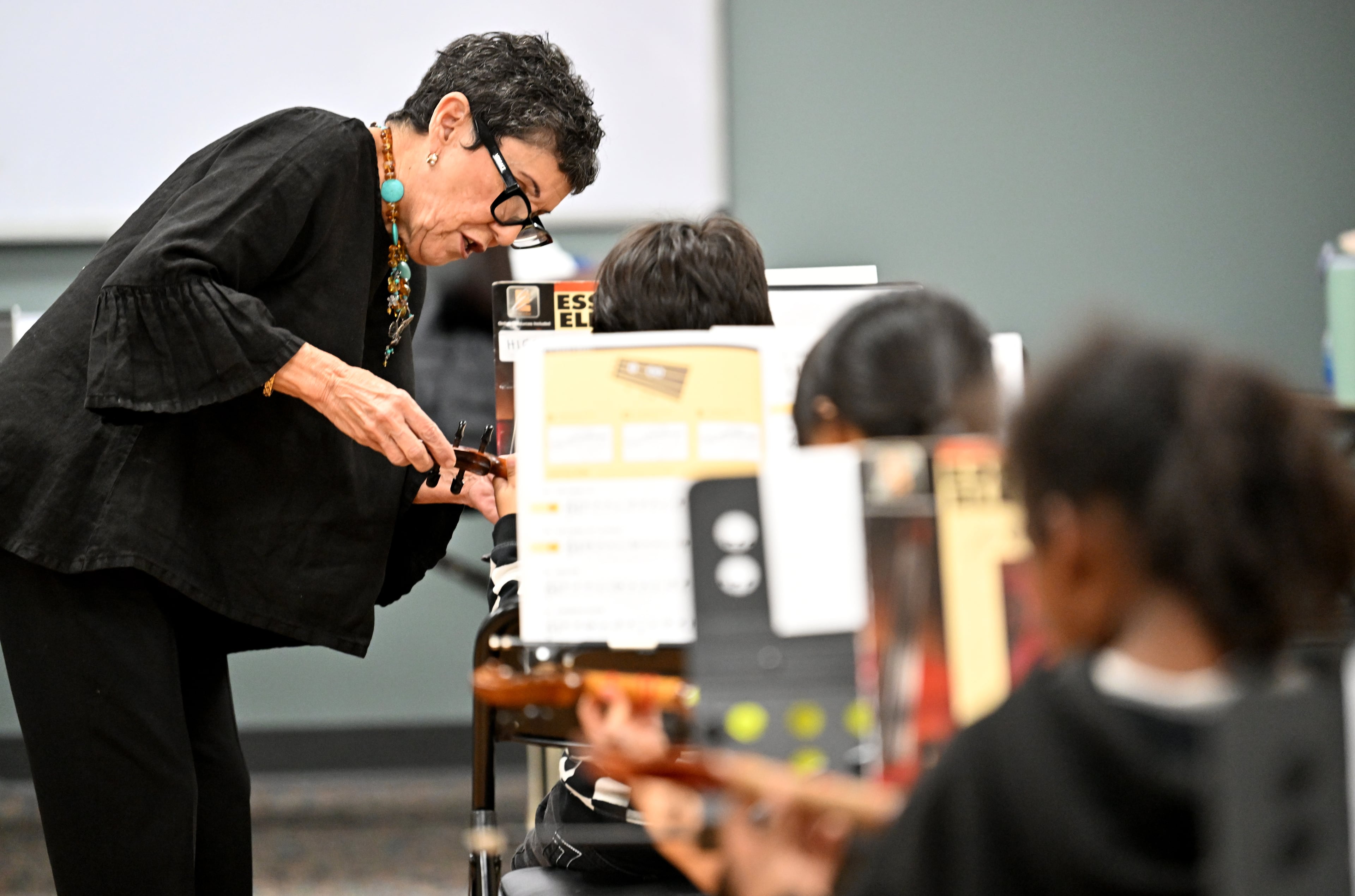 Juana Alzaga — known to her students as Miss Juanita — helps a member of the Buford Highway Orchestra Project with holding a violin bow the proper way at the Latin American Association on Thursday, Nov. 6, 2025, in Brookhaven. (Hyosub Shin/AJC)