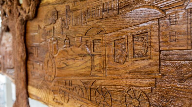 Made out of the trunk of a 100-year-old red oak tree that had died on the property of the Donaldson-Bannister Farm in Dunwoody, the 19-foot-long sculpture of Dunwoody's history was sculpted by Chamblee artist Tom Williams. (Courtesy of Dunwoody Preservation Trust)