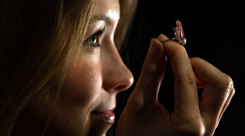 LONDON, ENGLAND - APRIL 07: A member of staff poses with 'The Unique Pink', the largest fancy vivid pink pear-shaped diamond ever offered at auction, during a press preview at Sotheby's auction house on April 7, 2016 in London, England. The diamond will be auctioned as part of the 'Magnificent Jewels and Noble Jewels' sale in Geneva on May 17 and is expected to fetch between 28-30 million USD. (Photo by Carl Court/Getty Images)