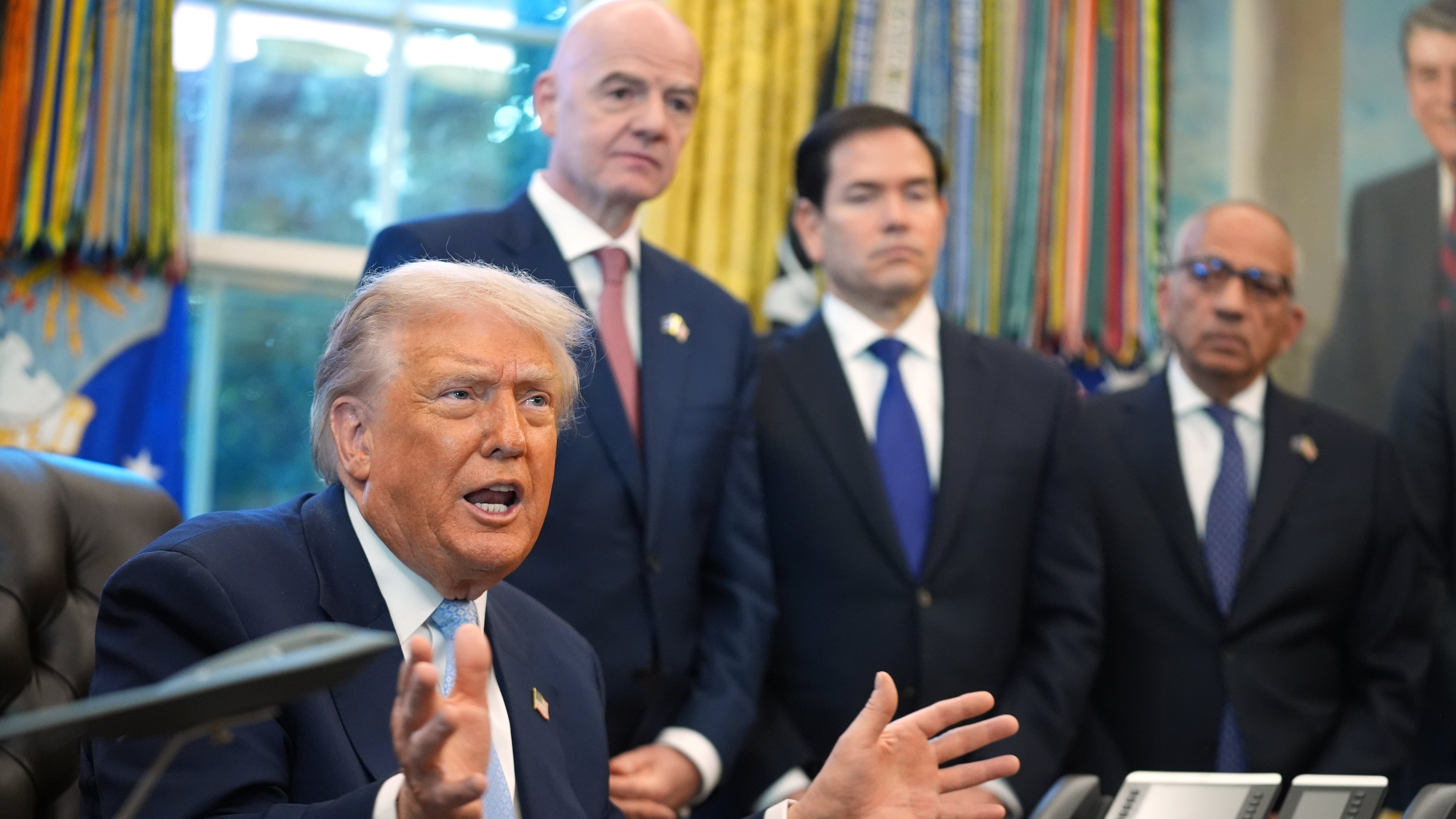 President Donald Trump answers questions from reporters during a meeting with the White House task force on the 2026 FIFA World Cup in the Oval Office of the White House, Monday, Nov. 17, 2025, in Washington, as FIFA President Gianni Infantino, Secretary of State Marco Rubio and FIFA senior adviser Carlos Cordeiro listen. (AP Photo/Evan Vucci)