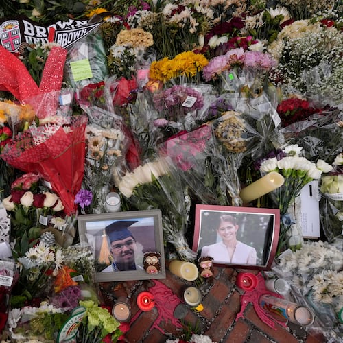 FILE - Photos of Brown University shooting victims Mukhammad Aziz Umurzokov, left, and Ella Cook, are seen amongst flowers at a makeshift memorial at the school's Van Wickle Gate, Dec. 17, 2025, in Providence, R.I. (AP Photo/Robert F. Bukaty, File)