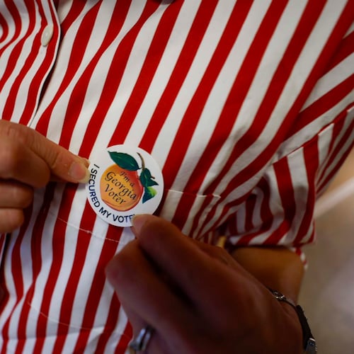A Georgia voter puts on her voting sticker after casting her ballot. Georgia Secretary of State Brad Raffensperger is set to remove nearly 500,000 voter registrations from the state's rolls. Officials say the registrations largely reflect people who have changed addresses, but voting rights activists say it threatens legitimate voters. (Miguel Martinez/AJC)