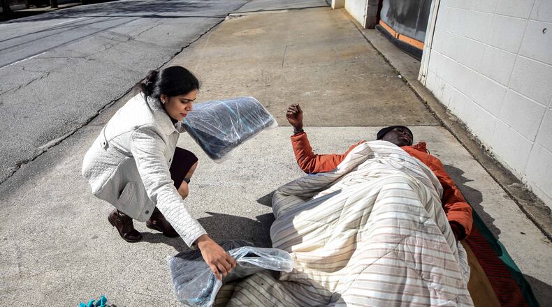 Pictured is Archita Ghosh laying a blanket near a homeless man on Ellis Street in Atlanta in 2019. The pandemic of 2020 has resulted increased homelessness that as spread to north Fulton. BRANDEN CAMP/SPECIAL