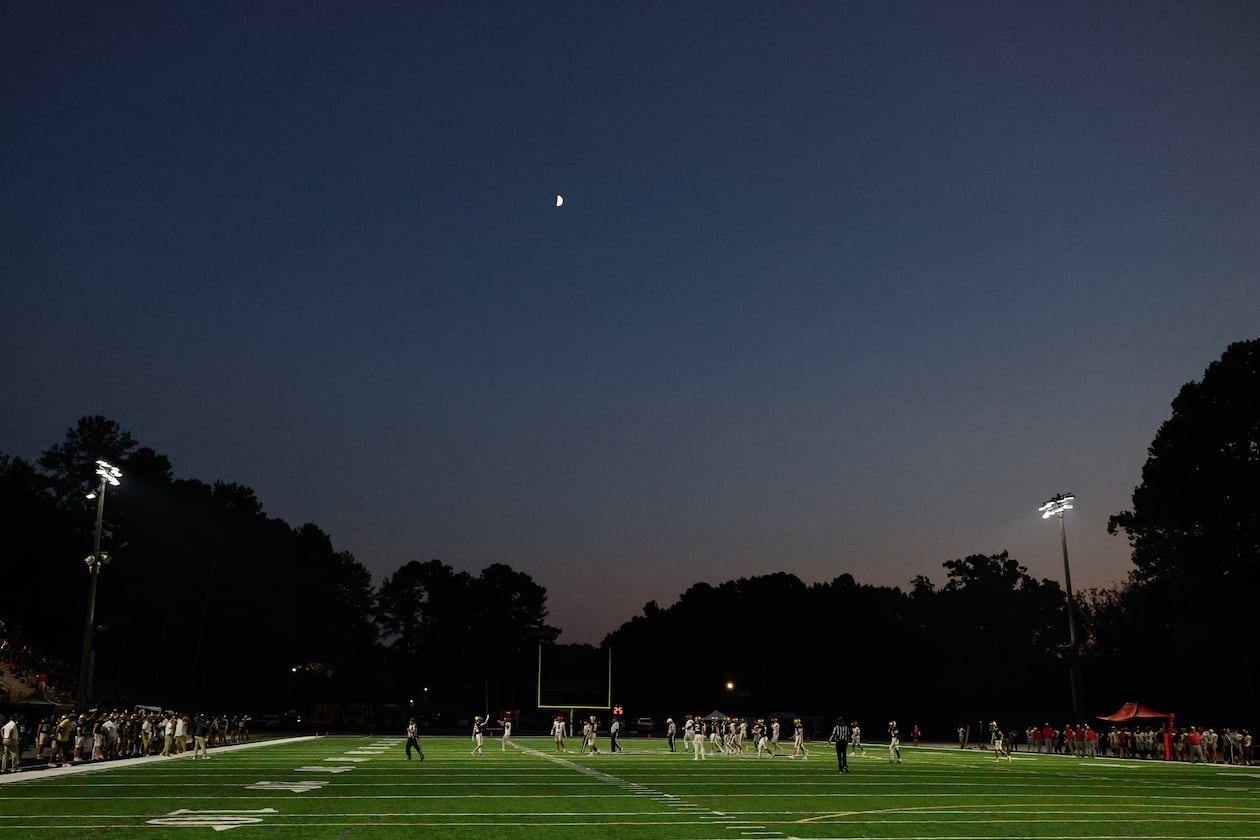 Teams play under a first quarter moon during the first half a high school football game between Winder-Barrow and St. Pius X, Friday, Sept. 18, 2026, in Atlanta. (Erik S. Lesser for the AJC)