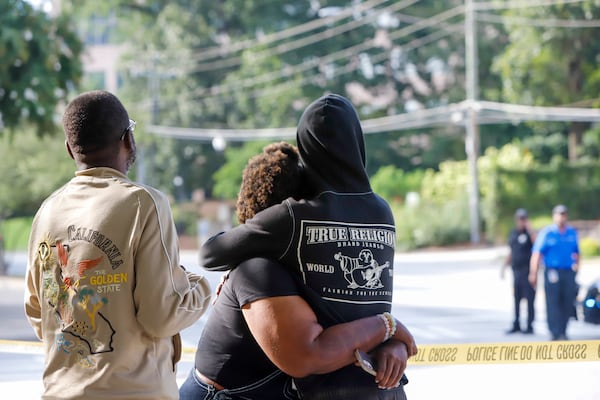 Pedestrians comfort each other after a shooting near the campuses of the Centers for Disease Control and Prevention and Emory University on Aug. 8. (Jenni Girtman/AJC)