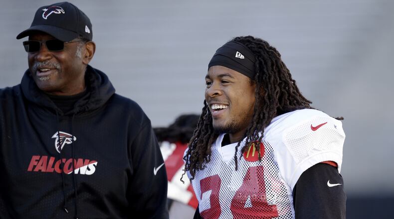 Atlanta Falcons running back Devonta Freeman (24) smiles as he talks with assistant coach Bobby Turner during a practice at the University of Washington Wednesday, Oct. 12, 2016, in Seattle. Rather than head home, the team traveled directly to Seattle after a football game Sunday in Denver, ahead of playing the Seattle Seahawks this coming Sunday in Seattle. (AP Photo/Elaine Thompson)