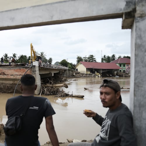 Men sit near a bridge collapsed during a flash flood in Pidie Jaya, Aceh province, Indonesia, Tuesday, Dec. 2, 2025. (AP Photo/Reza Saifullah)