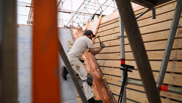 A coppersmith lays a new copper roof on the fire-damaged Old Stock Exchange building in Copenhagen, Denmark, Monday, June 23, 2025. (AP Photo/James Brooks)