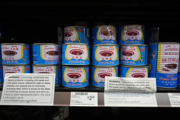 Cans of Szechuan sweet ban sauce sit with a California Proposition P65 chemicals warning label in an aisle at 99 Ranch Market, an Asian grocery store in Los Angeles Monday, April 7, 2025. (AP Photo/Damian Dovarganes)