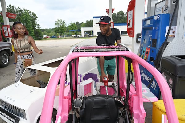 Mali “Sota” Hightower (right) fills up with gas as his neighbor Melissa Martin recognizes his modified Barbie car on Tuesday, June 9, 2026, in Ellenwood. (Hyosub Shin/AJC)