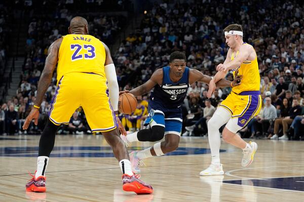 Minnesota Timberwolves guard Anthony Edwards (5) works toward the basket as Los Angeles Lakers forward LeBron James (23) and guard Austin Reaves (15) defend during the first half of Game 3 of an NBA basketball first-round playoff series, Friday, April 25, 2025, in Minneapolis. (AP Photo/Abbie Parr)
