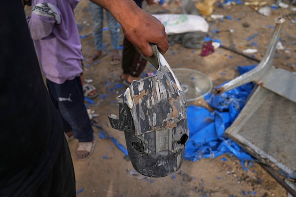 A man holds a piece of an explosive device as Palestinians inspect the damage caused by an Israeli strike that hit tents near Al-Aqsa Hospital in Deir al-Balah, in the central Gaza Strip, Saturday, May 17, 2025. (AP Photo/Abdel Kareem Hana)