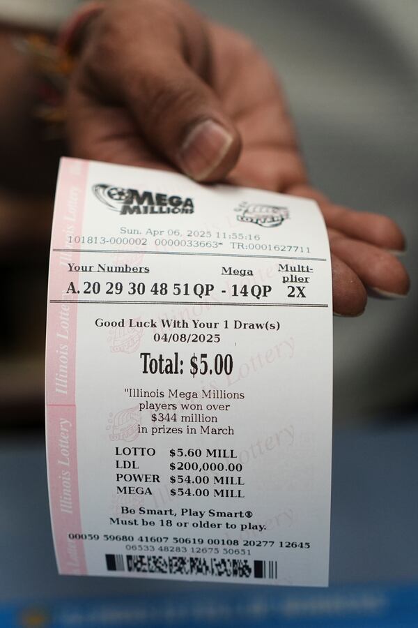 An employee of Mares Mart hands a Mega Millions lottery ticket to a customer in Chicago, Sunday, April 6, 2025. (AP Photo/Nam Y. Huh)