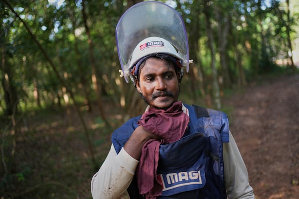 Vilvaraj Vinothan, who works for the demining agency Mine Advisory Group, wipes his sweat as he returns from the contaminated mining area to take a break in Mankulam, Sri Lanka, Wednesday, April 2, 2025. (AP Photo/Eranga Jayawardena)
