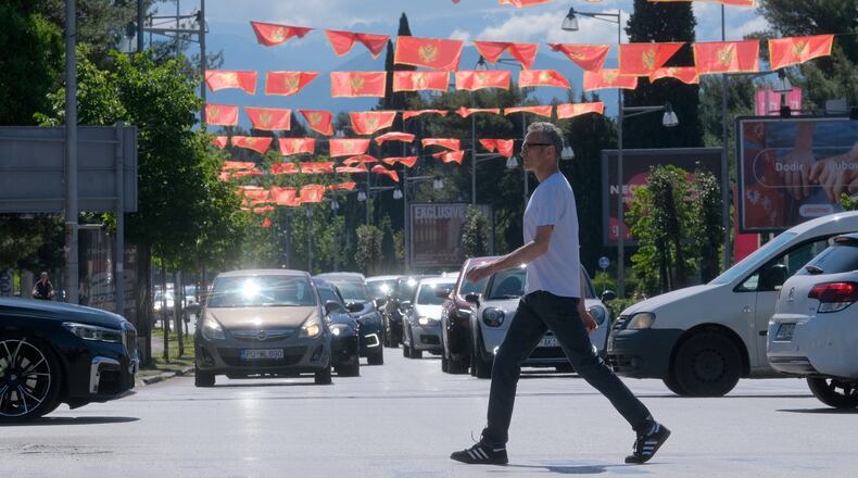 A man walks on a street decorated with national flags in Montenegro's capital Podgorica, Monday, May 18, 2026. (AP Photo/Risto Bozovic)