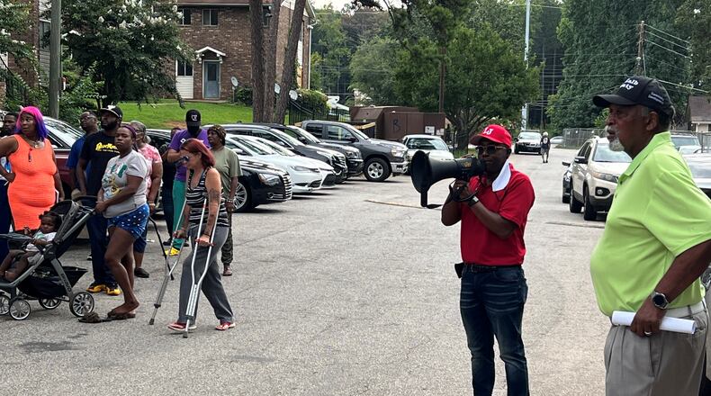 DeKalb County Commissioner Larry Johnson, at right with megaphone, speaks to a crowd of residents of the Forest at Columbia apartments during an event on Monday, Aug. 15.