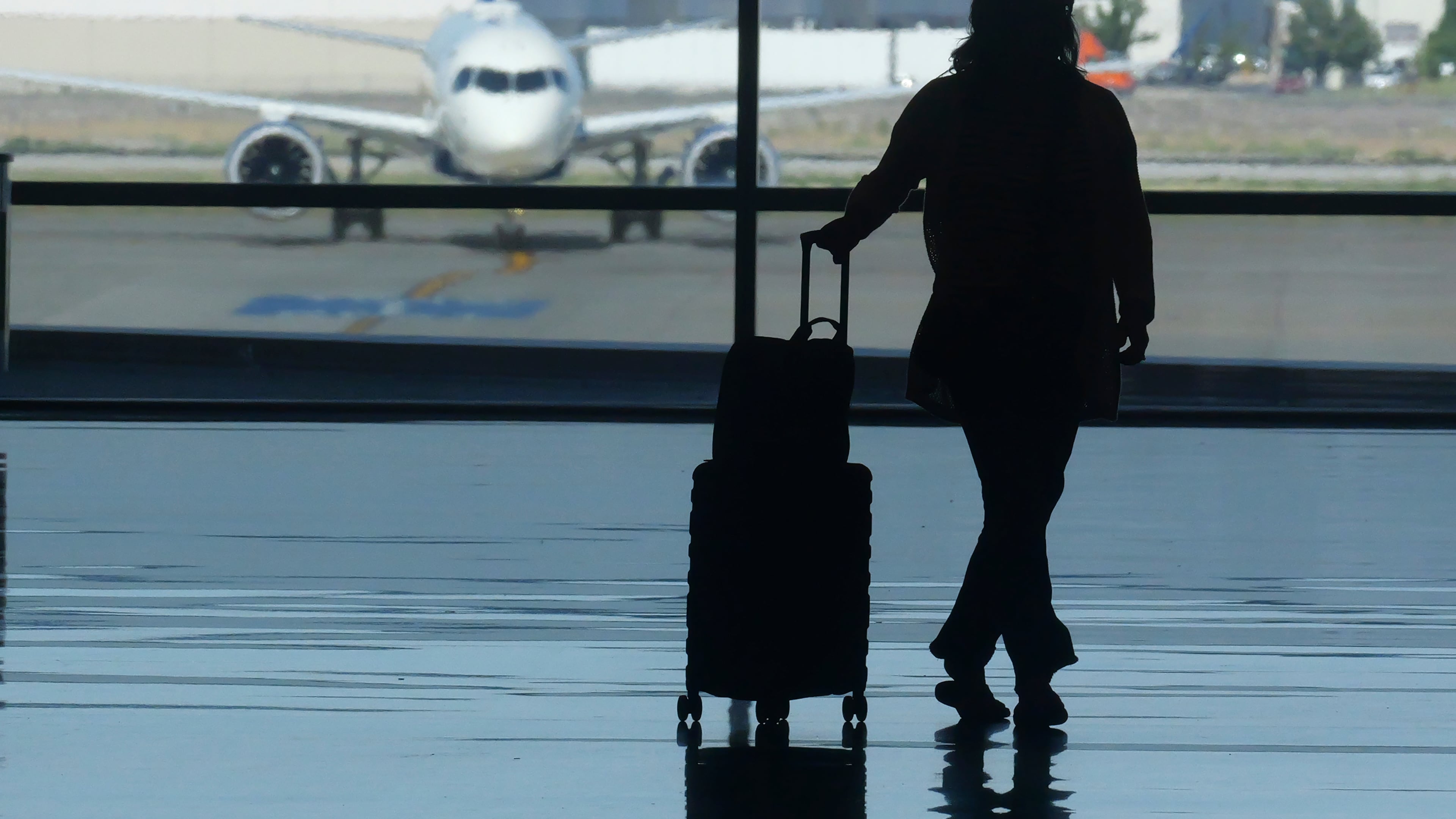 FILE - A traveler looks out at an airplane at Salt Lake City International Airport, in Salt Lake City, July 3, 2024. (AP Photo/Rick Bowmer, File)